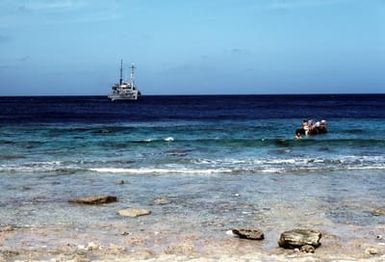 The salvage ship USS BOLSTER (ARS 38) prepares to set anchor offshore of the island