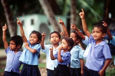 Children point to the sky as a 374th Airlift Wing aircraft passes over Peleliu during the delivery of boxes of gifts to islanders of the Federated States of Micronesia. Flown by crews from the 345th and the 21st Airlift Squadrons, the C-130 is participating in Christmas Drop '92, the 40th anniversary of the humanitarian effort. Every Christmas since 1952, food, clothing, tools and toys donated by residents of Guam have been delivered by air to 40 Micronesian islands