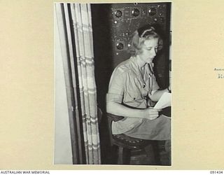 LAE, NEW GUINEA, 1945-05-07. PRIVATE G. HOOPER, WHO DID ALL THE BROADCASTING OF SHIP'S ORDERS, SEATED AT THE PUBLIC ADDRESS SYSTEM TABLE ABOARD THE MV DUNTROON. SHE IS ONE OF THE 342 AWAS EN ROUTE ..