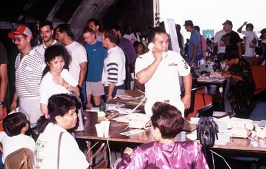 A Navy petty officer talks on the telephone at an information desk as hundreds of military and civilian personnel arrive from the Philippine Islands after the June 10 eruption of Mount Pinatubo deposited more than four inches of volcanic ash on the area, dispupting base operations. More than 20,000 evacuees have been removed as a part of the U.S. military's Operation Fiery Vigil