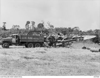 LAE, NEW GUINEA. 1943-10-04. UNITED STATES TROOPS AND NEW GUINEA NATIVES COLLECTING METAL FROM A CRASHED JAPANESE ZERO AIRCRAFT FOR SALVAGE