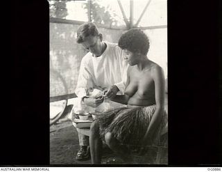 KIRIWINA, TROBRIAND ISLANDS, PAPUA. 1943-11-27. CORPORAL R. J. PETERSON OF INNISFAIL, QLD, NURSING ORDERLY, ATTENDING TO VICTORIA, A NATIVE GIRL WHO HAS AN INJURED HAND AND IS AT NO. 3 MEDICAL ..