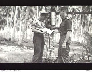 MILILAT, NEW GUINEA. 1944-07-16. THE SIGNAL MASTER OF HEADQUARTERS SIGNALS, 5TH DIVISION HANDING A DESPATCH TO A UNIT DON.R. (DESPATCH RIDER) OUTSIDE THE UNIT SIGNALS OFFICE