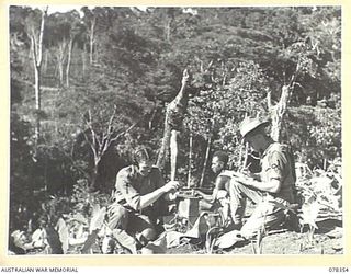 TAMKAIDAN, NEW BRITAIN. 1945-01-14. AN ALLIED INTELLIGENCE BUREAU PATROL POST HIGH UP IN THE MOUNTAINS VX110802 SERGEANT C.J. MOYNIHAN (1) AND NX44720 CORPORAL A.P. COLMAN (2) CAN BE SEEN MAKING ..