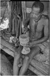 Carving: M'lapokala carving a wooden bowl with a stand, probably for tourist trade, other carvings (l)