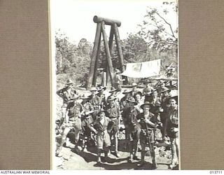 Engineers and signallers of the 25 Brigade stand in a bomb crater near the pylon of a rope bridge at Wairopi. Identified are: QX14351 Corporal Herbert Haylock (second row from the front, first on ..