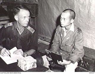 RABAUL, NEW BRITAIN, 1945-12-21. CAPTAIN W. SAUNDERS, PAYMASTER, CASH OFFICE, 11 DIVISION (1), TAKING OVER THE FINANCES OF THE JAPANESE IMPERIAL NAVY IN THIS AREA, FROM LIEUTENANT TAKSHI, JAPANESE ..