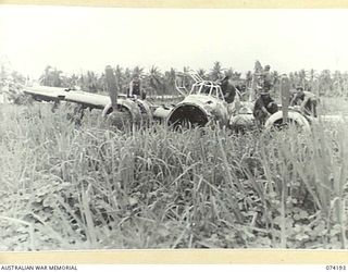 HANSA BAY, NEW GUINEA. 1944-06-21. AUSTRALIAN TROOPS EXAMINING THE WREAKAGE OF A BURNT OUT JAPANESE BOMBER FOUND ON THE EDGE OF THE AIRSTRIP AFTER THEY OCCUPIED THE AREA