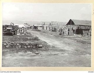 CAPE WOM, NEW GUINEA, 1945-05-29. A GENERAL VIEW OF AREA SHOWING TRUCK ACTIVITIES AND BUILDINGS IN VARIOUS STAGES OF COMPLETION AT ONE OF THE LARGE DUMPS AT THE FIELD MAINTENANCE CENTRE