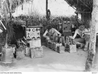 DUMPU, RAMU VALLEY, NEW GUINEA. 1943-11-29. VX20650 LANCE CORPORAL L. J. LEE (LEFT) AND VX45485 SIGNALMAN H. E. SEWELL (RIGHT) AT WORK IN THE BATTERY CHARGING SECTION OF HEADQUARTERS, 7TH ..