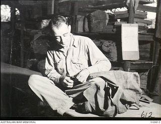 VIVIGANI, GOODENOUGH ISLAND, PAPUA. C. 1943-10. IN THE PARACHUTE SECTION, NO. 30 BEAUFIGHTER SQUADRON RAAF, LEADING AIRCRAFTMAN H. MARKS, BONDI, NSW, HAND PACKS A PARACHUTE AFTER IT HAD BEEN ..