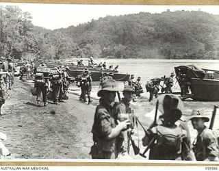 LANGEMAK BAY, NEW GUINEA, 1943-10-28. MEMBERS OF THE 2/24TH AUSTRALIAN INFANTRY BATTALION BOARDING BARGES AT THE BEACHHEAD. SHOWN ARE:- NX127076 SIGNALLER B.N. DARE (1); VX34930 SIGNALLER W.F. KEMP ..