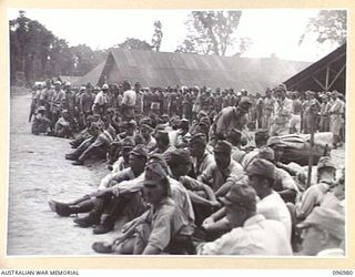 TOROKINA, BOUGAINVILLE. 1945-09-23. JAPANESE TROOPS WHO HAD ARRIVED FROM NAURU ISLAND TWO DAYS PREVIOUSLY, LINED UP ALONG BARBED WIRE IN A COMPOUND OF THE CONCENTRATION CAMP, CHOP CHOP TRAIL, TO ..