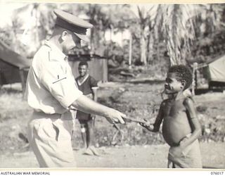 LAE, NEW GUINEA. 1944-09-18. TX2002 BRIGADIER J. FIELD, DSO, ED, COMMANDING, 7TH INFANTRY BRIGADE PRESENTING AN AXE TO ONE OF THE FIVE NATIVE BOYS WHO ESCORTED HIM AND MAJOR J. SUMMERTON BACK TO ..