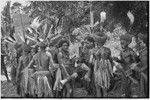 Pig festival, wig ritual: men wearing red wigs and feather valuables, folded mat held between split stick (l) used to carry feather valuables