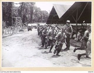 TOROKINA, BOUGAINVILLE. 1945-09-23. MAJOR A.T. BEECH, 9TH INFANTRY BATTALION, DIRECTING JAPANESE NAVAL TROOPS AT THE DOUBLE INTO A SEARCHING HUT FOR SEARCHING BY OFFICERS OF 9TH INFANTRY BATTALION, ..