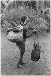 Woman walking off loaded down; fresh cooking bamboos in top of bag