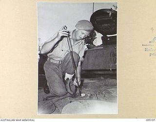 TOROKINA, BOUGAINVILLE, 1945-08-14. TROOPER L. EDGTTON DIPPING FUEL TANKS ON AN M24 LIGHT TANK DURING ACTIVITIES OF THE BRITISH WAR OFFICE TRIALS TEAM (TANKS)