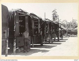 BOUGAINVILLE. 1945-08-30. STOREMEN OF 113 BRIGADE ORDNANCE FIELD PARK AUSTRALIAN ARMY ORDNANCE CORPS CHECKING SUPPLIES IN STORE VEHICLES LINED UP IN THE FIELD PARK