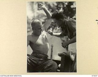 ALEXISHAFEN, NEW GUINEA. 1944-05-22. Q134055 PRIVATE W. COONEY (1), BEING TREATED FOR A RASH BY NX120797 PRIVATE H.A. BRETT (2), A REGIMENTAL AID POST MEDICAL ORDERLY OF THE 35TH BATTALION AT THE ..