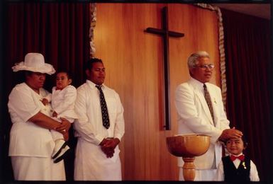 The Reverend Laau I. Tanielu places his hand on the head of Uelese Tai, whom he has just christened