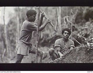 BULLDOG ROAD, NEW GUINEA, 1943-07-17. TWO NATIVES BREAKING ROCKS AT THE 33 MILE POINT