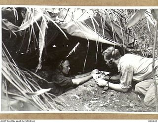 FINSCHHAFEN AREA, NEW GUINEA. 1943-11-07. WX6034 GUNNER J. M. HARRIES OF DOWERIN, WA, (LEFT) AND VX103831 GUNNER A. J. MCCALLUM OF DEVINESH, VIC, (RIGHT), OPERATING THE WIRELESS SET AT ..