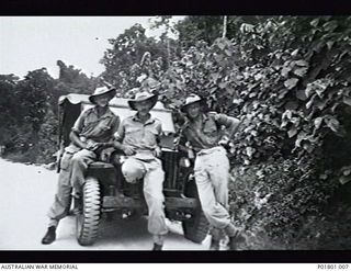 Jacquinot Bay, New Britain. c.1946. An informal group portrait of three Australian soldiers on the front of a Jeep quarter ton four wheel drive truck. Left to right; unknown, R. J. Crack and ..