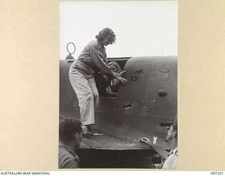 BORAM AIRSTRIP, WEWAK AREA, NEW GUINEA. 1945-09-28. MISS A. BARROW STEPS WARILY ALONG THE WING OF A BEAUFORT BOMBER AIRCRAFT BEFORE BEING ASSISTED TO THE GROUND ON HER ARRIVAL AT HEADQUARTERS 6 ..