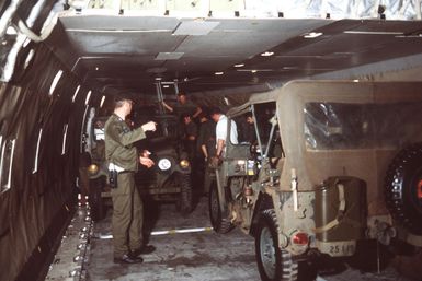 Members of the 619th Military Airlift Support Squadron secure US Army M151 vehicles aboard a Flying Tigers 747 contract aircraft. The vehicles are being shipped to Korea for use during exercise TEAM SPIRIT '79