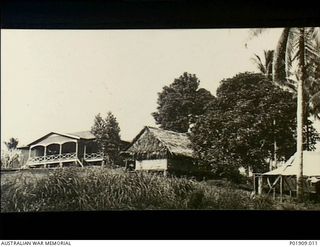 Milne Bay, New Guinea. 1943. The Anti-Aircraft group headquarters at Milne Bay. Three buildings are visible, one with a canvas roof, another with a thatched grass roof, and a more standard western ..