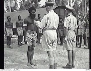 LUNGGA, NEW GUADALCANAL, BRITISH SOLOMON ISLANDS PROTECTORATE. 1943-10-14. LIEUTENANT COMMANDER I. PRYCE-JONES, THE DISTRICT SUPERVISING INTELLIGENCE OFFICER, WITH SUB LIEUTENANT R. STEWART, THE ..