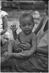 Baby waving to the camera, sitting on woman's lap