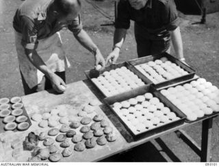 WEWAK AREA, NEW GUINEA, 1945-06-13. TPR E.P. HUNTER, 2/9 COMMANDO SQUADRON (1), PLACING BREAD ROLLS ON TRAYS BEFORE THEY ARE PLACED IN THE OVEN DURING A COURSE CONDUCTED BY LHQ COOKING AND CATERING ..