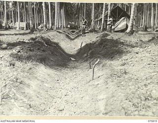 SIAR, NEW GUINEA. 1944-09-11. NX118603 LIEUTENANT J.L. JOHNSTON (1) AND VX63284 CAPTAIN J.K. GALLAGHAN (2) OF THE 113TH BRIGADE WORKSHOP INSPECTING THE NEW MAIN DRAIN DUG THROUGH THE UNIT CAMP AREA