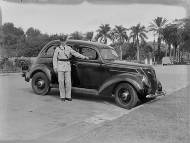 [Portrait of a man next to an automobile]