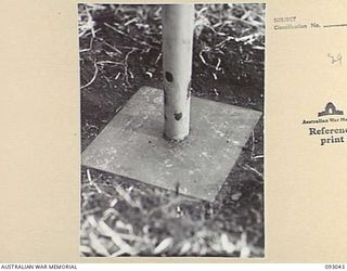 LAE AREA, NEW GUINEA, 1945-06-15. THE STEEL BASE PLATE OF AN IMPROVISED AERIAL MAST AT 19 L OF C SIGNALS. THIS IS AN ORDINARY 15 INCH BY 15 INCH STAY PLATE RESTING ON THE SURFACE OF THE GROUND WITH ..