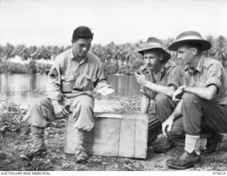 MILILAT, NEW GUINEA. 1944-07-14. 39079360 STAFF SERGEANT S. SUGIMOTO, UNITED STATES ARMY AND A MEMBER OF THE ALLIED TRANSLATOR AND INTERPRETER SECTION (1) TRANSLATING THE PRINTING ON CAPTURED ..