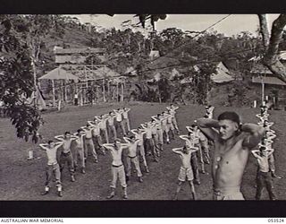 SOGERI VALLEY, NEW GUINEA, 1943-06-26. STUDENTS OF THE NEW GUINEA FORCE SCHOOL OF SIGNALS ON THEIR DAILY PHYSICAL TRAINING PARADE WITH INSTRUCTOR VX136099 SERGEANT J. W. JORGENSON IN FOREGROUND