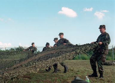 US Army (USA) Soldiers assigned to the 21ST Signal Company, and US Air Force (USAF) Airmen assigned to the 206TH Combat Communication Squadron, set up camouflaged netting for the communication center at Orote Point, Guam during Exercise TANDEM THRUST 99