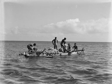 [Pacific Island men fishing off a canoe]