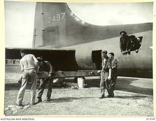 1942-12-07. NEW GUINEA. A 105MM M-3A1 HOWITZER COMPLETE WITH SPARES, TRACTOR AND AMMUNITION IS UNLOADED SOMEWHERE IN THE BATTLE AREA. THE GUN CREW ALSO CAME WITH THE GUN. PICTURE SHOWS A PORTION OF ..