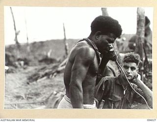 WEWAK AREA, NEW GUINEA, 1945-07-14. AN ANGAU NATIVE "BOSS BOY" WHO BROUGHT HIS CARRIER TRAIN ON "THE BLOT" 20 MINUTES BEHIND THE ASSAULT TROOPS DURING THE ATTACK AGAINST THE FEATURE BY A COMPANY, ..