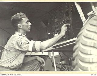 KATIKA, NEW GUINEA. 1944-03-31. NX65187 SIGNALMAN C. STRAHAN, B AUSTRALIAN CORPS SIGNALS, TUNING IN THE TRANSMITTER UNIT OF THE 188F, (UNITED STATES ARMY 191F), WIRELESS TRANSMITTER-RECEIVER. WHEN ..