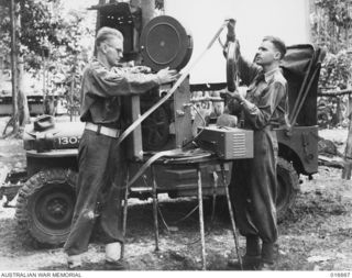 NEW GUINEA. 17 MARCH 1944. MOBILE JEEP PICTURE UNITS BRING A LAUGH AND A MEMORY OF OTHER DAYS TO TROOPS IN FORWARD POSITIONS IN THE RAMU VALLEY. SGT. DON GOLDRICK OF MATRAVILLE N.S.W. AND SGT. ALEC ..