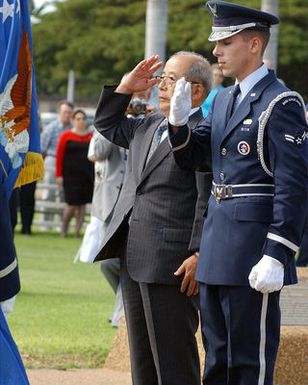 Japanese World War II Veteran Mr. Iwashita, President of the Zero Fighter Pilots Association and US Air Force (USAF) AIRMAN First Class (A1C) Timothy Nichols, a member of the Hickam AFB, Hawaii (HI) Honor Guard Team, pay respects to fallen soldiers during a Flagpole Ceremony held to commemorate the attack on Hickam Field during the Japanese invasion