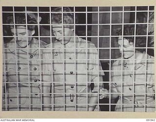 LAE, NEW GUINEA, 1945-05-18. PERSONNEL FROM THE AUSTRALIAN WOMEN'S ARMY SERVICE BARRACKS, TAKING PART IN A CONDUCTED TOUR ARRANGED BY ARMY AMENITIES SERVICE, ADMIRING AN EXHIBIT OF HANDCRAFTS MADE ..