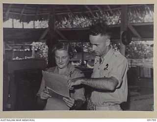 LAE, NEW GUINEA. 1945-05-15. PRIVATE P. WISHART (1), AT "A" BRANCH, HEADQUARTERS FIRST ARMY, RECEIVING INSTRUCTION IN HER NEW JOB FROM SERGEANT R.J. SEARLE (2). A FEW DAYS AFTER THEIR ARRIVAL FROM ..