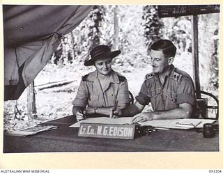 BOUGAINVILLE, 1945-06-18. LT-COL M.G. EDISON, 109 CASUALTY CLEARING STATION, MOTUPENA POINT (2), CHECKING REPORTS WITH NURSING SISTER CAPTAIN ELIZABETH IRENE UREN (1), WHO IS IN CHARGE OF THE ..