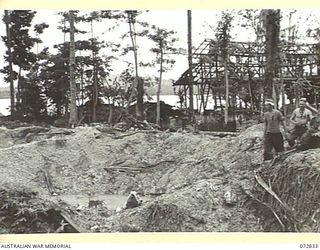 ALEXISHAFEN, NEW GUINEA. 1944-04-30. LARGE BOMB CRATERS AND SHATTERED BUILDINGS TESTIFY TO THE EFFECTIVENESS OF THE ALLIED BOMBING ON THE NORTH SHORE OF THE HARBOUR